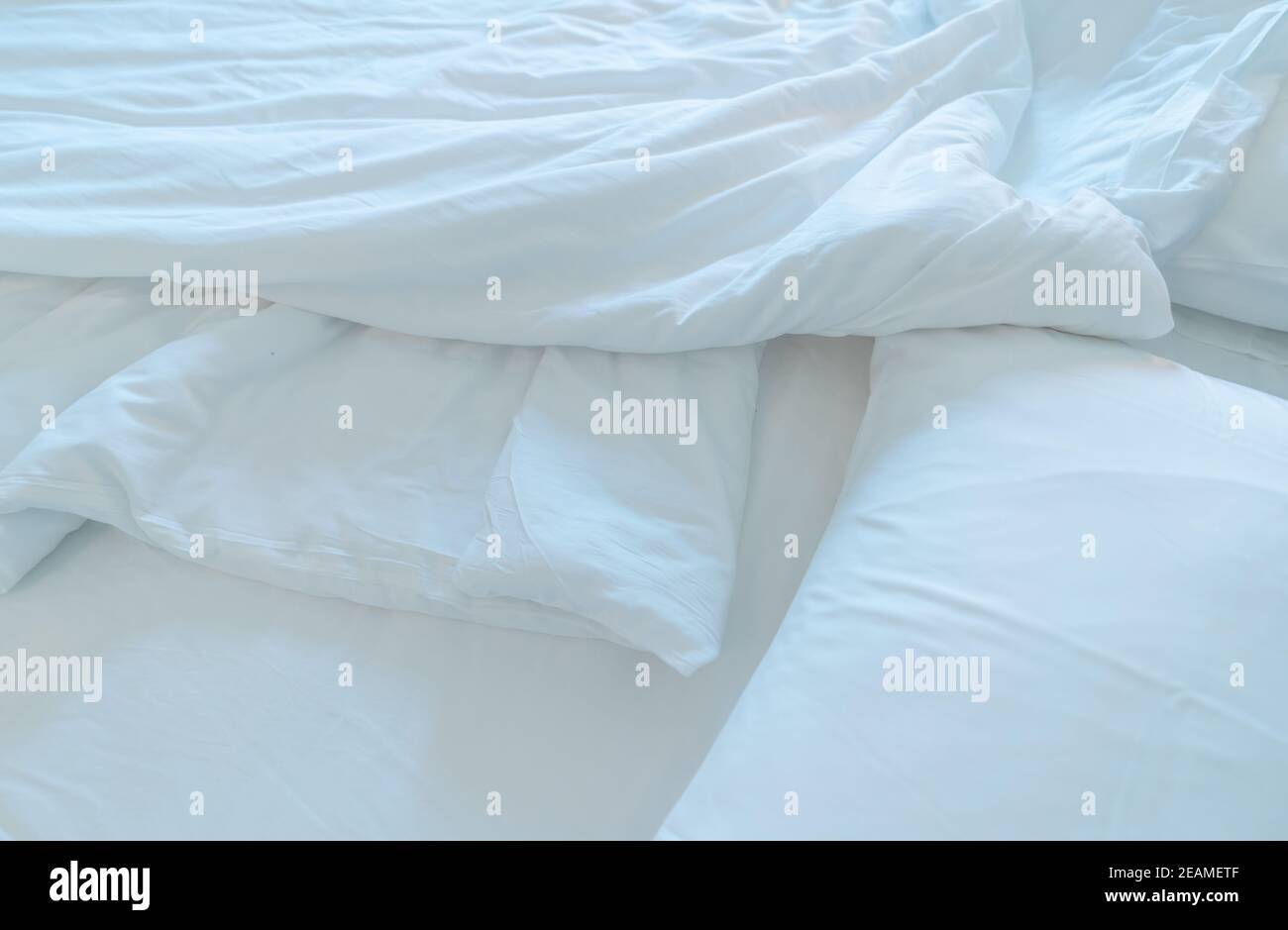 Letto bianco comfort e morbido cuscino nella camera da letto moderna. Coperta di biancheria bianca nella camera da letto dell'hotel. Dettaglio closeup della caucciosa coperta bianca dopo il risveglio al mattino. Comodo letto con soffice piumone bianco. Foto Stock