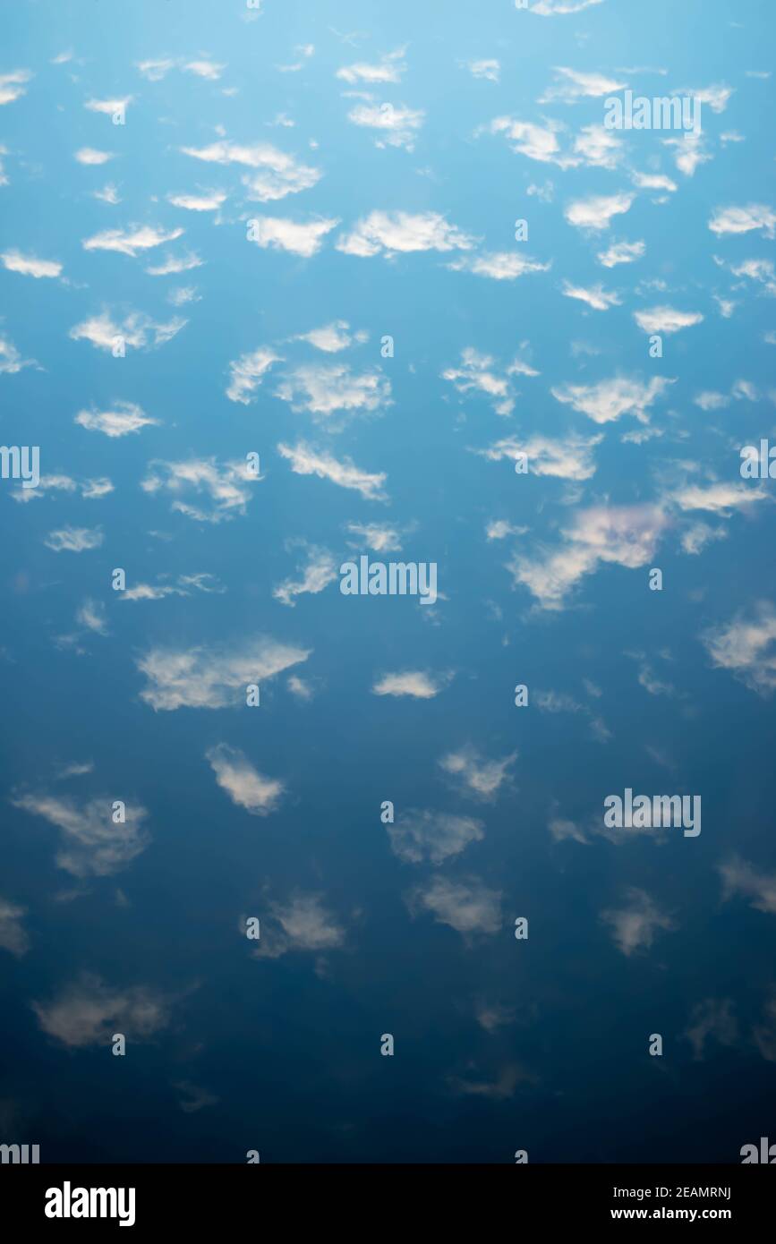 Cielo blu e nuvole soffici si riflettono in una serena lago Foto Stock