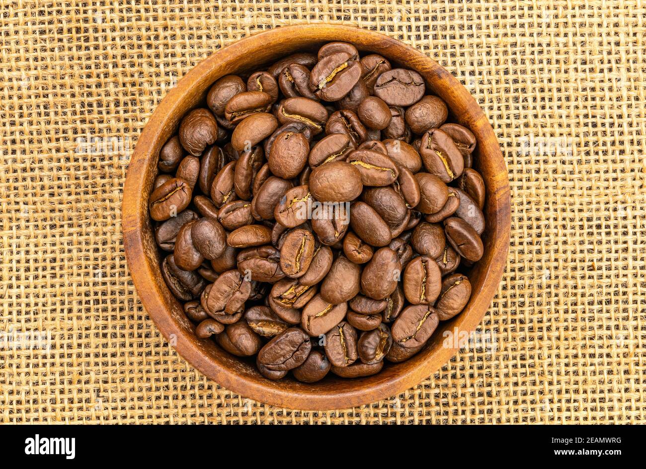 Vista dall'alto dei chicchi di caffè in un recipiente di legno su un panno. Chicchi di caffè tostati in un recipiente di legno. Foto Stock