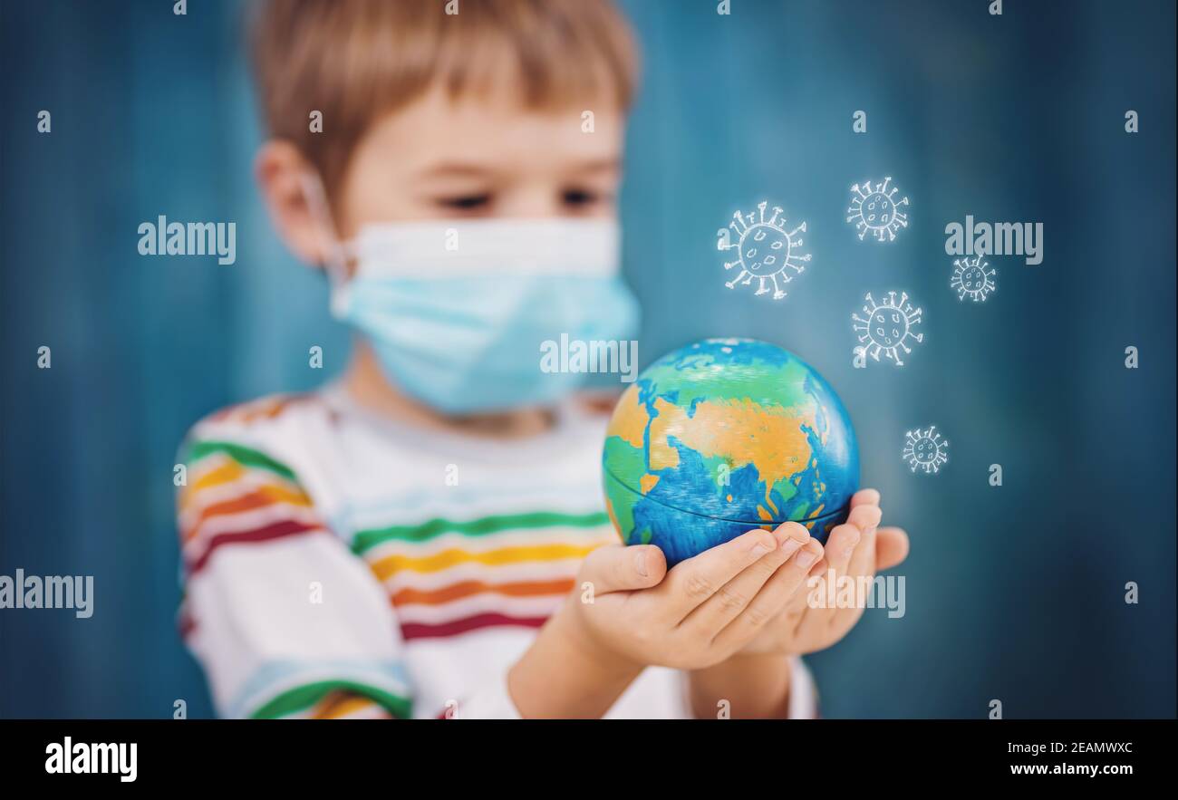 Ragazzo in maschera medica di protezione del viso in interni su sfondo blu Foto Stock