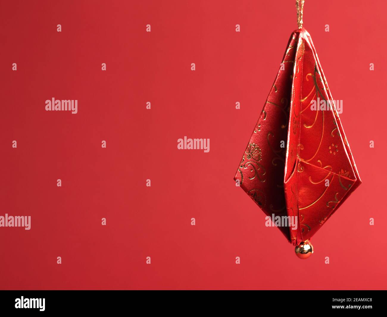 Decorazioni per alberi di Natale piegate da una bella decorazione rossa e oro carta su sfondo rosso Foto Stock