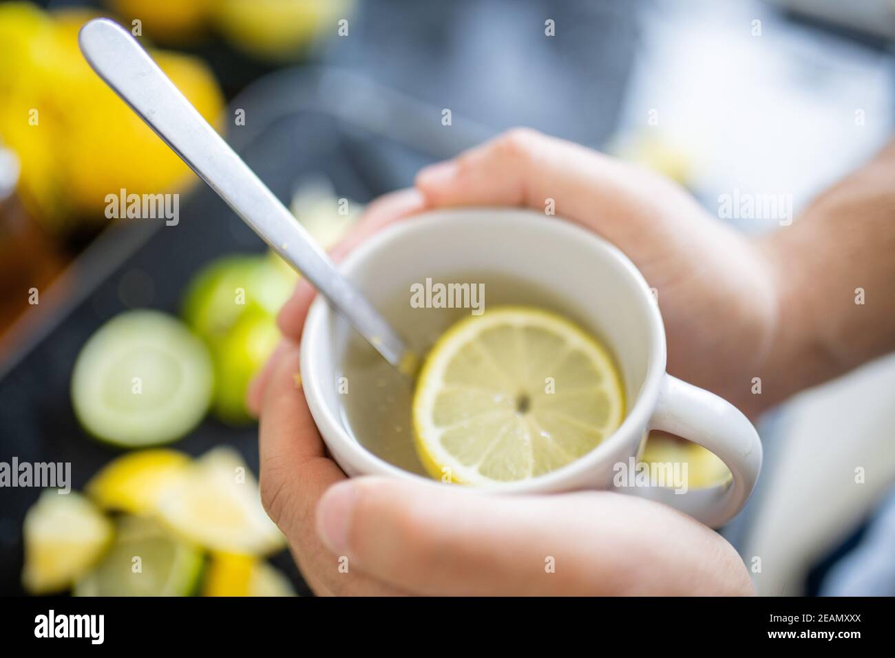 Mani maschili che tengono una tazza di tè al limone sopra la lime sezioni Foto Stock