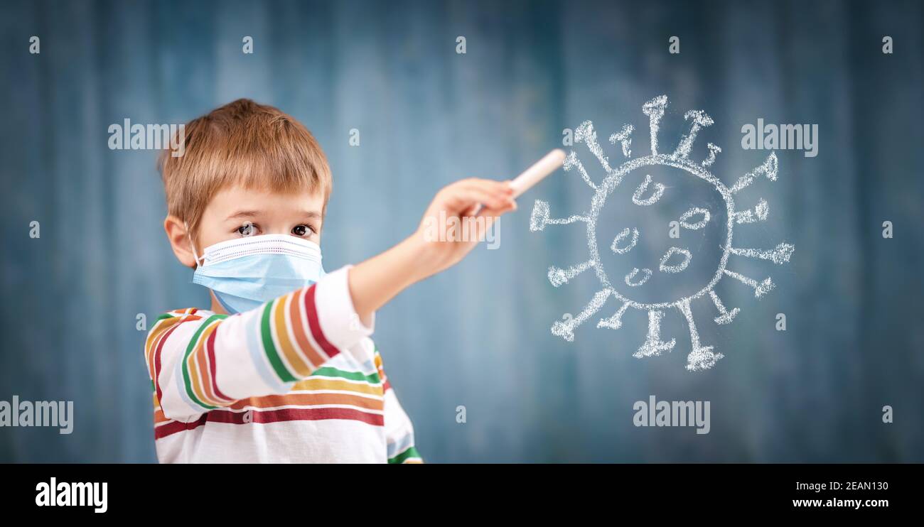 Ragazzo in maschera medica di protezione del viso in interni su sfondo blu. Foto Stock