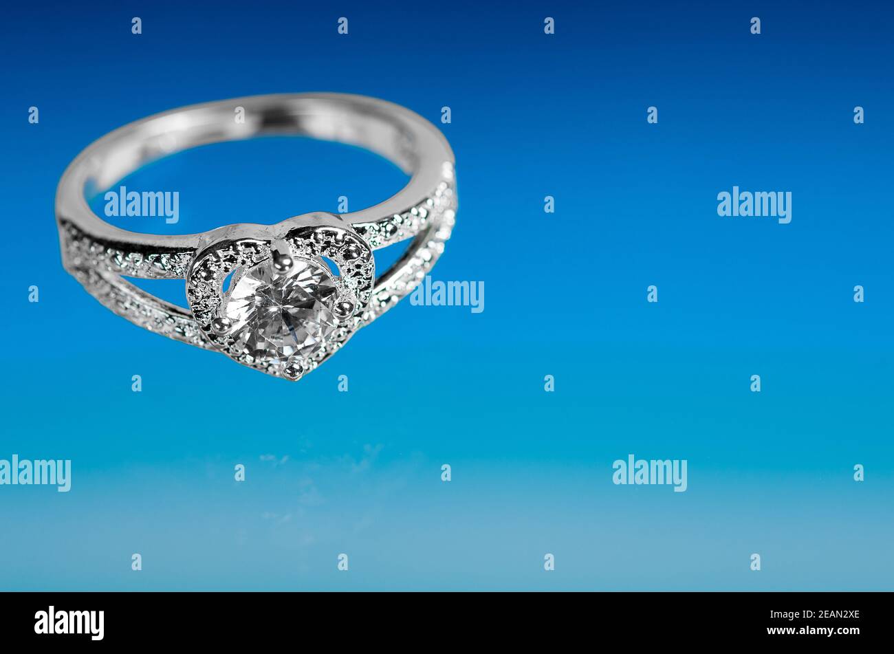 Anello a forma di cuore con un cristallo su sfondo blu. Foto Stock
