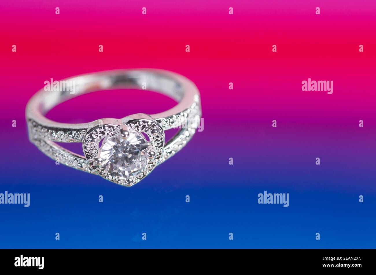 Anello a forma di cuore con cristallo su sfondo rosso-blu. Foto Stock