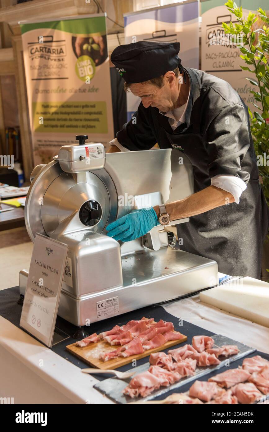 Un uomo che affetta carne e prosciutto di parma su un commerciale  Affettatrice in occasione di un evento alimentare a Bologna Italia Foto  stock - Alamy