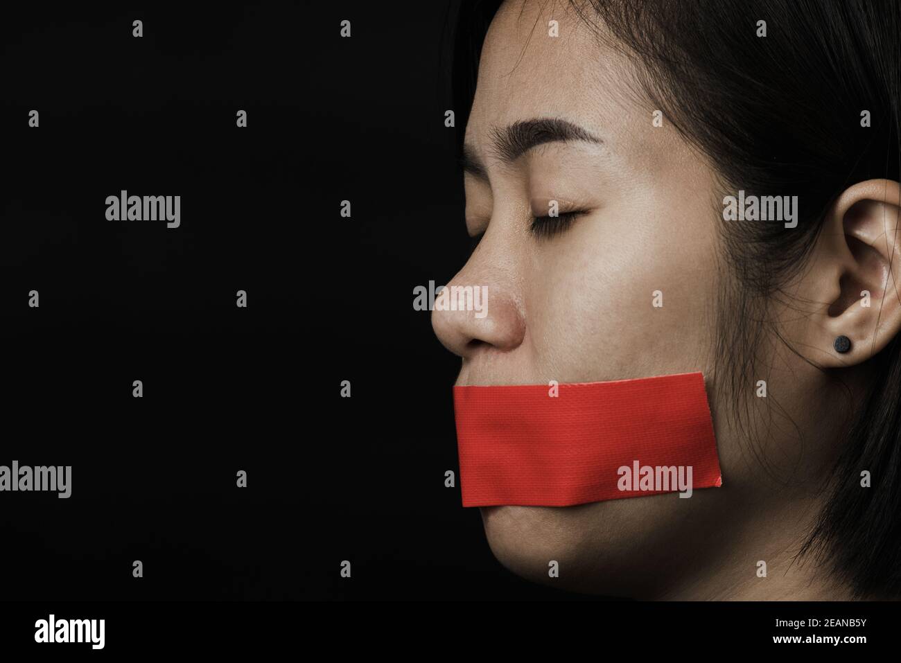 Donna asiatica bendfold bocca di avvolgimento con nastro adesivo rosso Foto Stock
