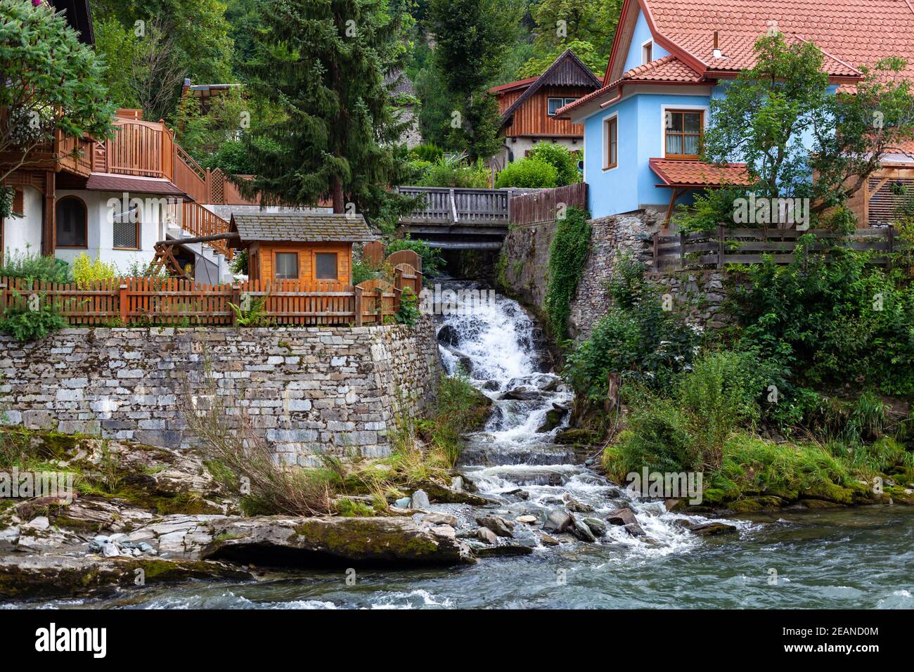 villaggio sulla riva di un fiume di montagna con un cascata Foto Stock