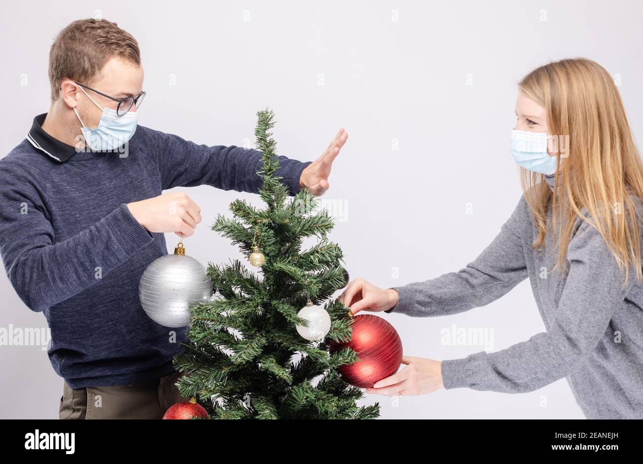 Coppia cercando di mantenere la distanza sociale mentre decorando l'albero di Natale Foto Stock