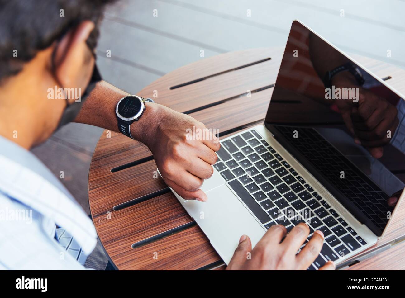 uomo che lavora con un computer portatile e guarda l'orologio durante l'orario della riunione di lavoro della direzione Foto Stock