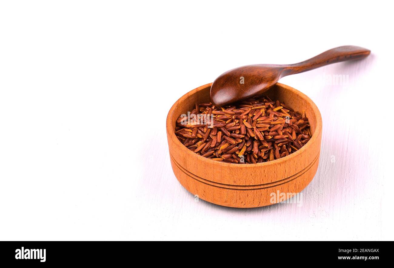 Il riso marrone in una tazza di legno su un tavolo da pranzo bianco. Foto Stock