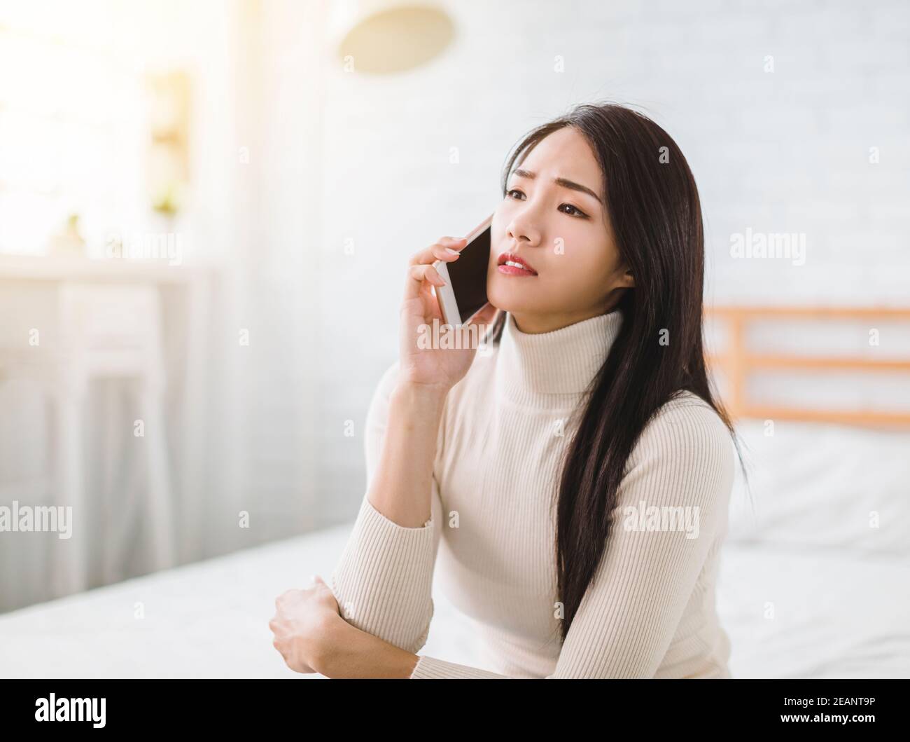 giovane donna infelice che parla sul telefono cellulare a casa Foto Stock