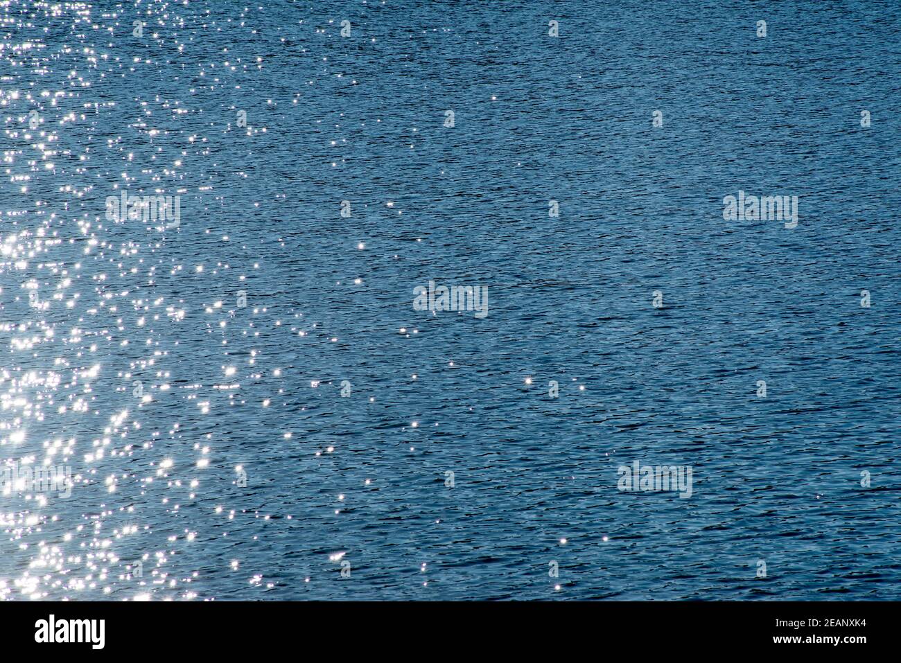 Fuori centro scintilla su superficie blu increspata acqua - copia spazio Foto Stock