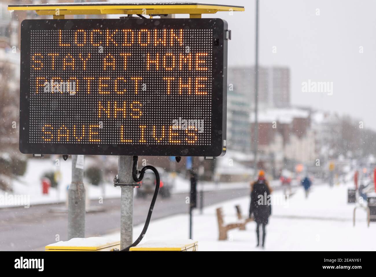 Matrix sign warning of COVID 19 lockdown misure in Southend on Sea, Essex, UK, con neve da Storm Darcy. Rimani a casa, proteggi lo slogan NHS Foto Stock