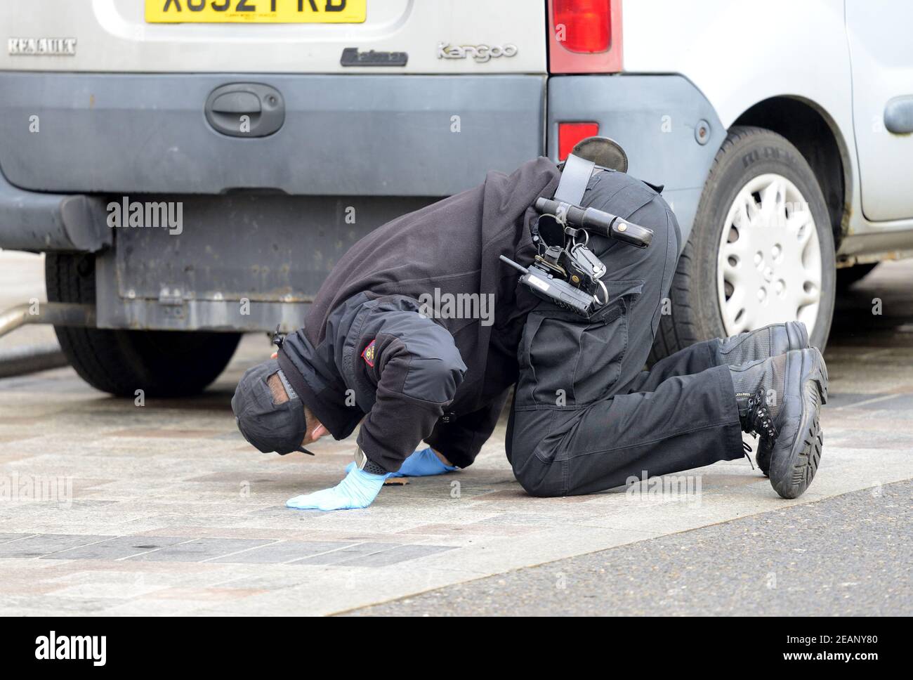 Maidstone, Kent, Regno Unito. Ufficiali di polizia che conducono una ricerca in High Street dopo una pugnalata la sera precedente. Ufficiale che controlla sotto un'automobile (4° F Foto Stock