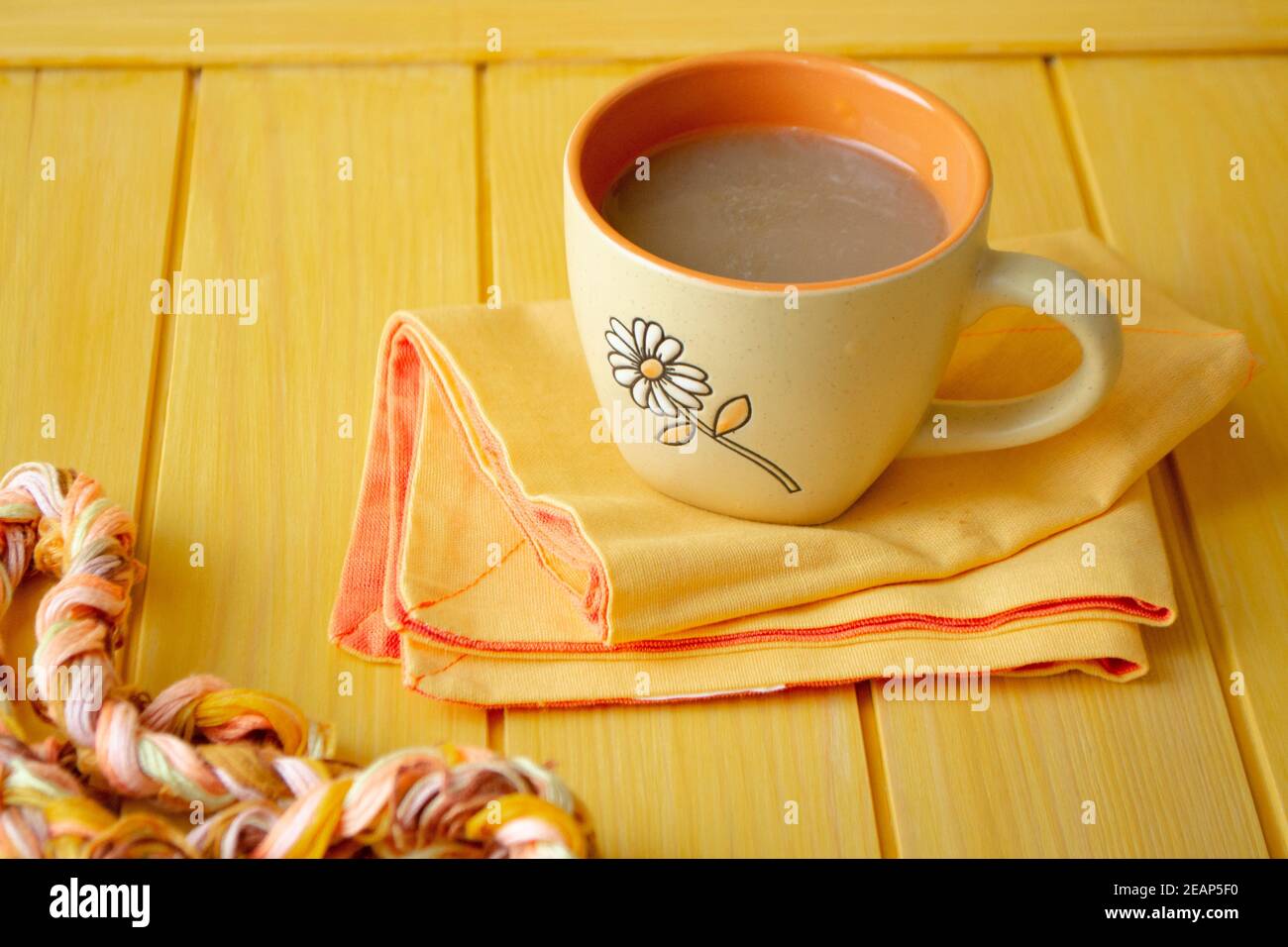 Cappuccino con arte del caffè in tazza arancione su tavolo di legno giallo. Foto Stock