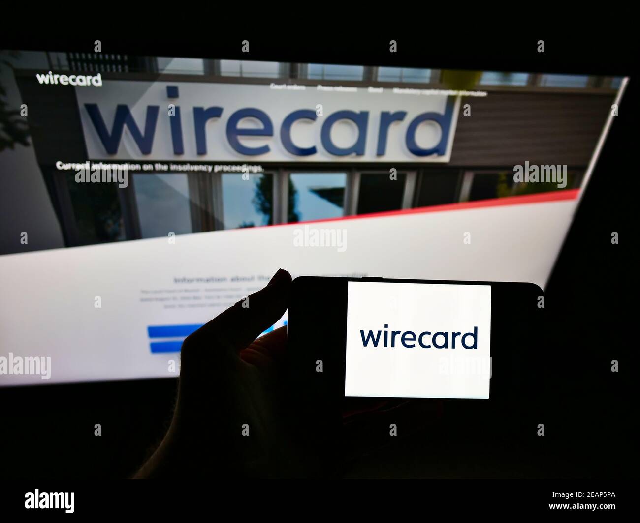 Titolare di un telefono cellulare con logo della società tedesca di pagamenti e servizi finanziari Wirecard AG davanti alla pagina web. Focus sul display del cellulare. Foto Stock