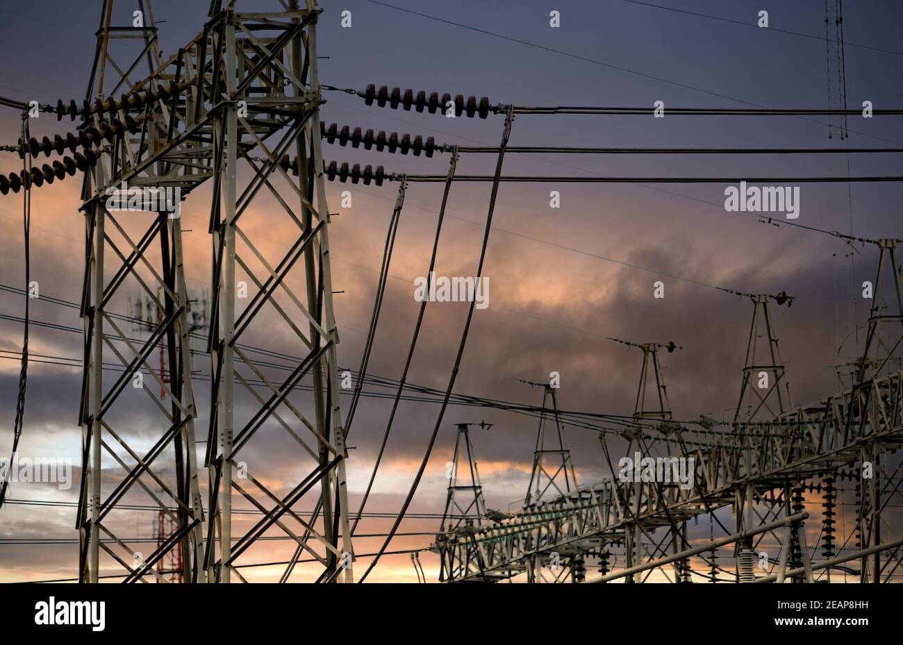 Pilone elettrico ad alta tensione e filo elettrico contro cielo tempestoso e nuvole. Torre di rete ad alta tensione con cavo. Linee di trasmissione sulla torre di rete ad alta tensione. Potenza elettrica trifase. Foto Stock