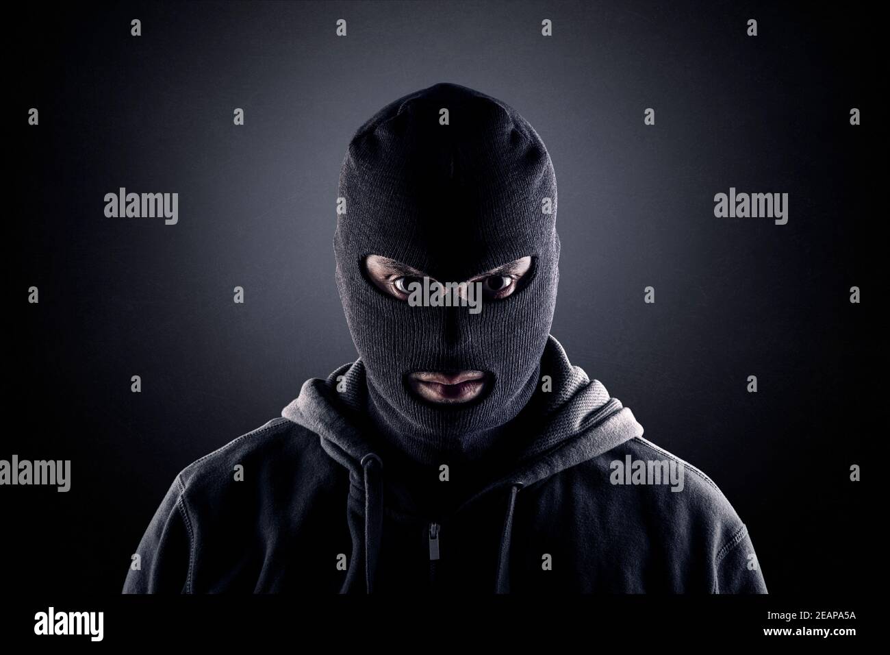 Criminale che indossa balaclava nera e felpa con cappuccio al buio Foto  stock - Alamy