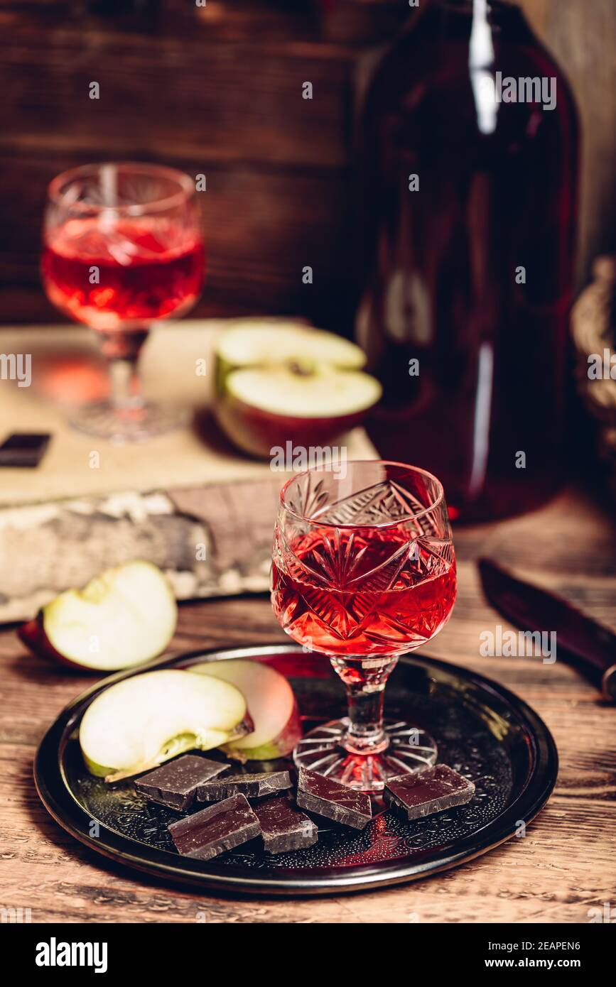 Bicchiere di nalivka al ribes rosso fatta in casa con fette di mela e cioccolato Foto Stock