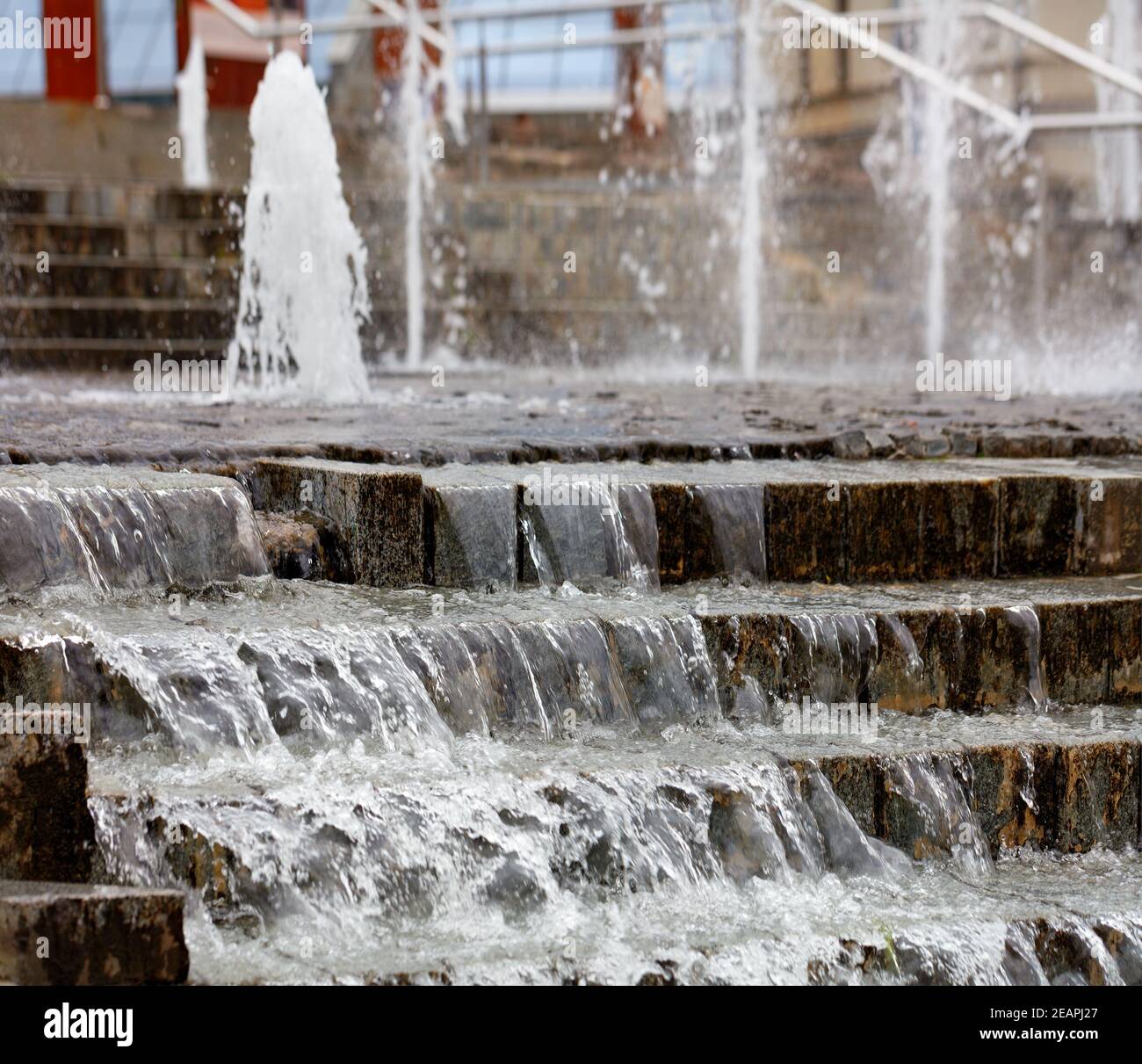 Denso ruscelli di acqua traboccano sul bordo della fontana in pietra a gradini. Foto Stock