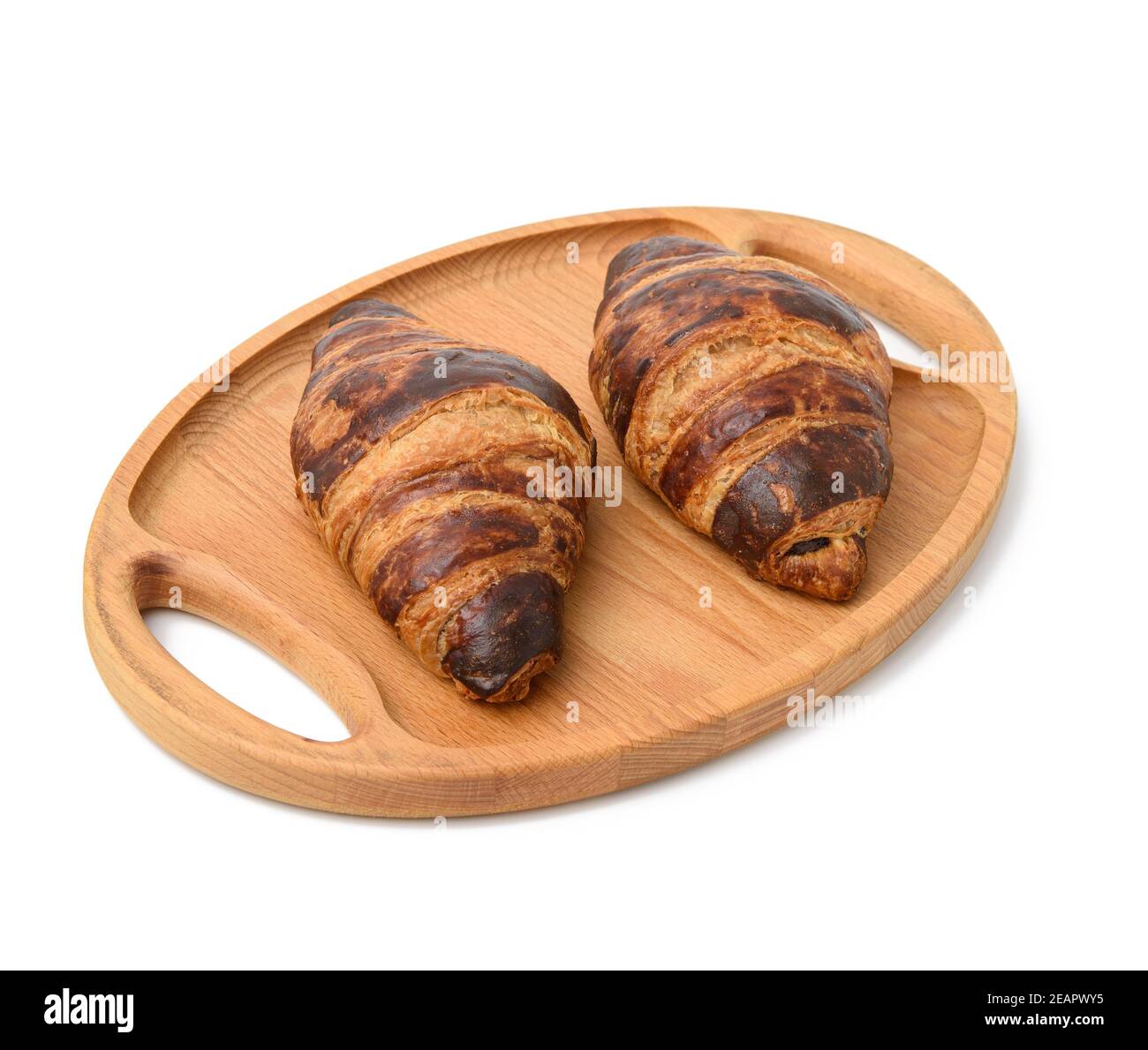 due croissant al forno si trovano su un vassoio di legno Foto Stock