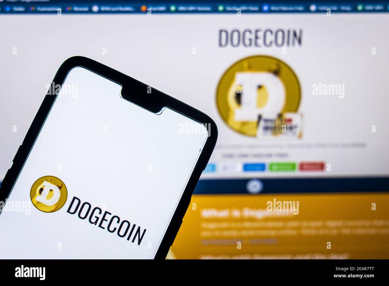Logo Dogecoin su un sito web aganista smartphone dogecoin su un pc in background. Il valore di Dogecoin è stato spiked AFT Foto Stock
