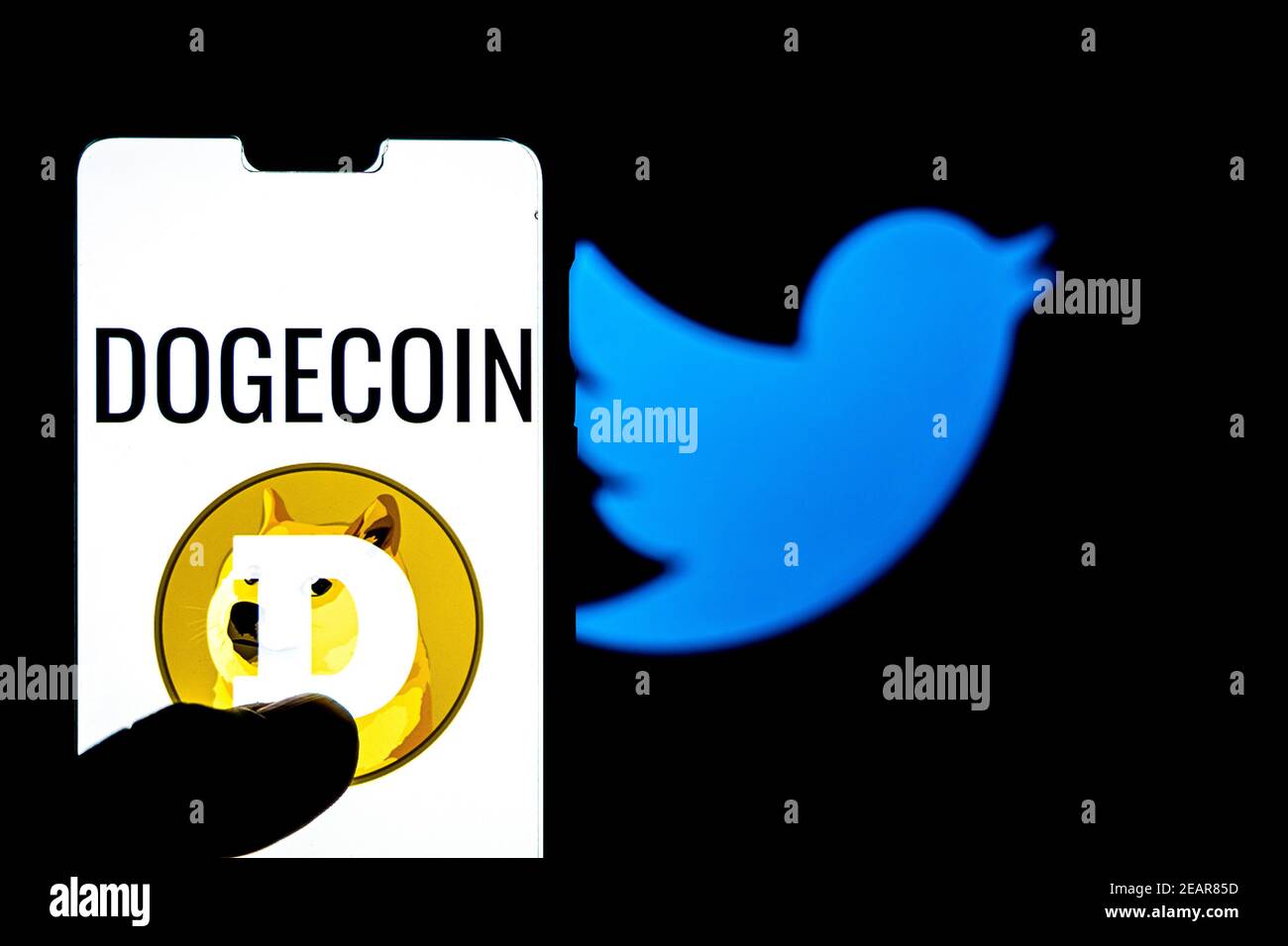 Logo Dogecoin su uno smartphone aganista twitter logo sullo sfondo. Il valore di Dogecoin è cullato dopo Elon Musk Foto Stock