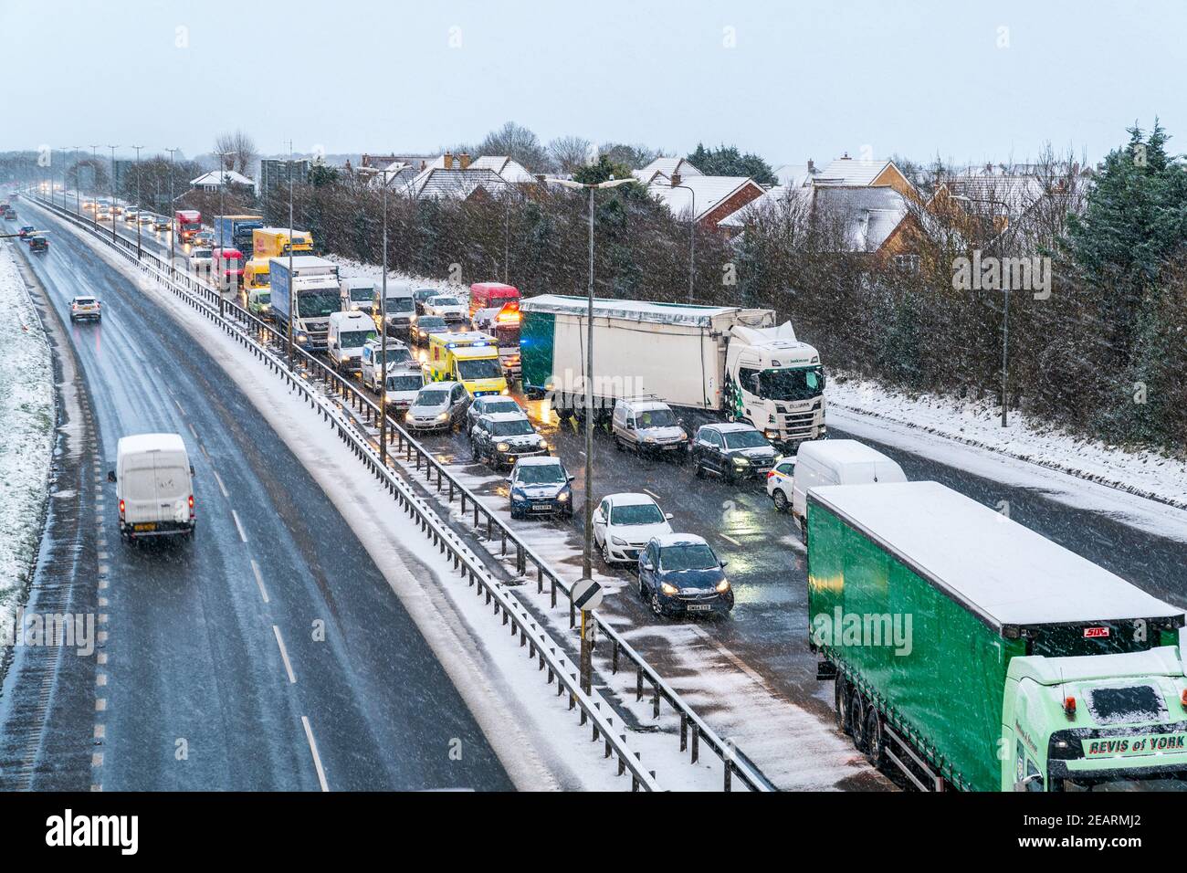 Due corsie di traffico in sosta con un'ambulanza che cerca di attraversare il centro delle due corsie su una strada a doppia carreggiata britannica coperta di neve a seguito di un incidente. Ingorgo sulla A299, Thanet Way, sulla carrozza di Londra. Foto Stock