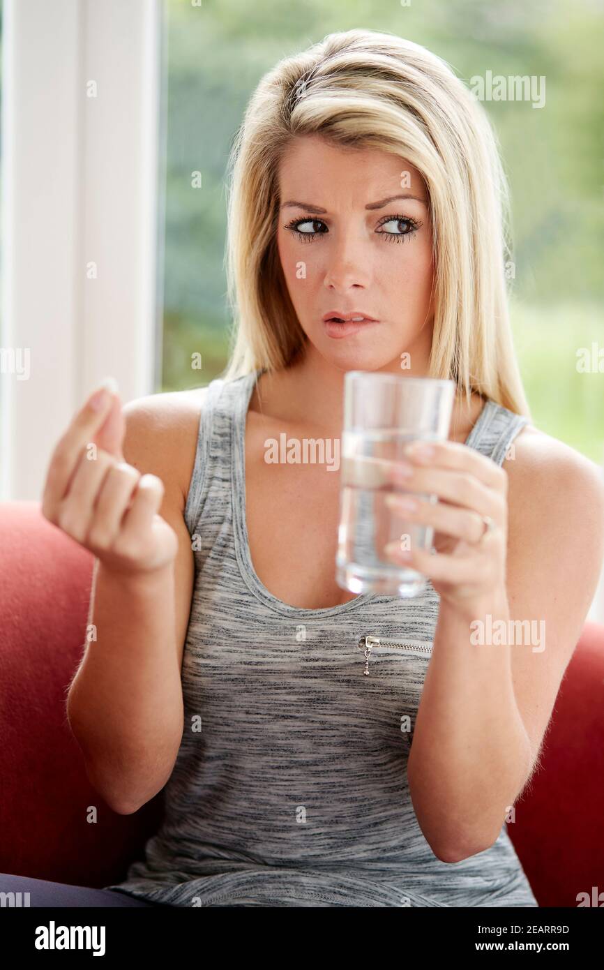 Donna che prende la compressa con un bicchiere d'acqua Foto Stock