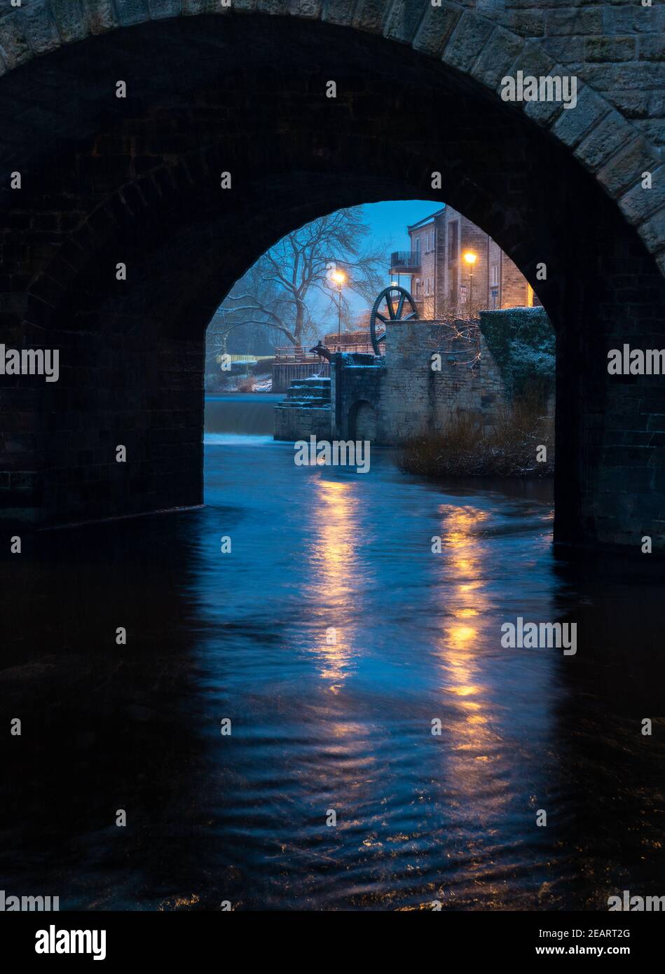 Vista notturna attraverso un arco della storica Wetherby ponte sul fiume Wharfe verso il weir Foto Stock