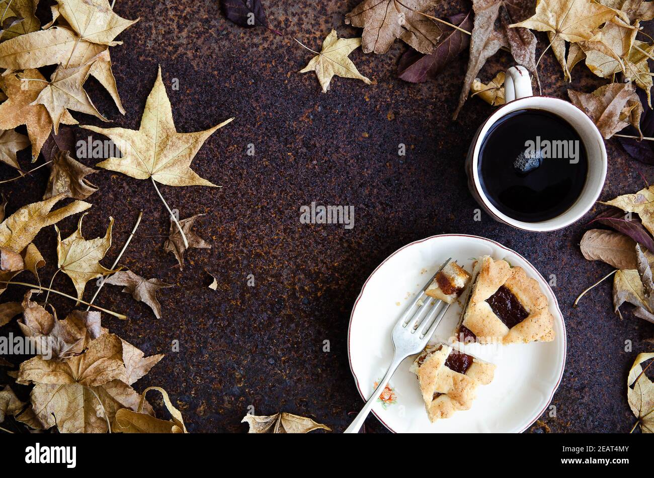 Pezzi di pastafrola su un piatto bianco con forchetta e una tazza di tè, con foglie di albero. Foto Stock