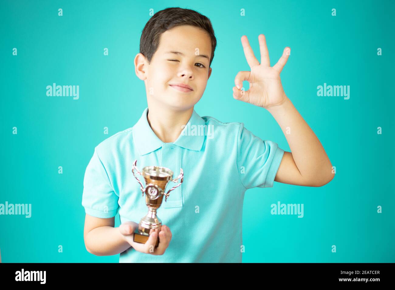 Giovane caucasico che tiene un trofeo con la posa di festa Foto Stock