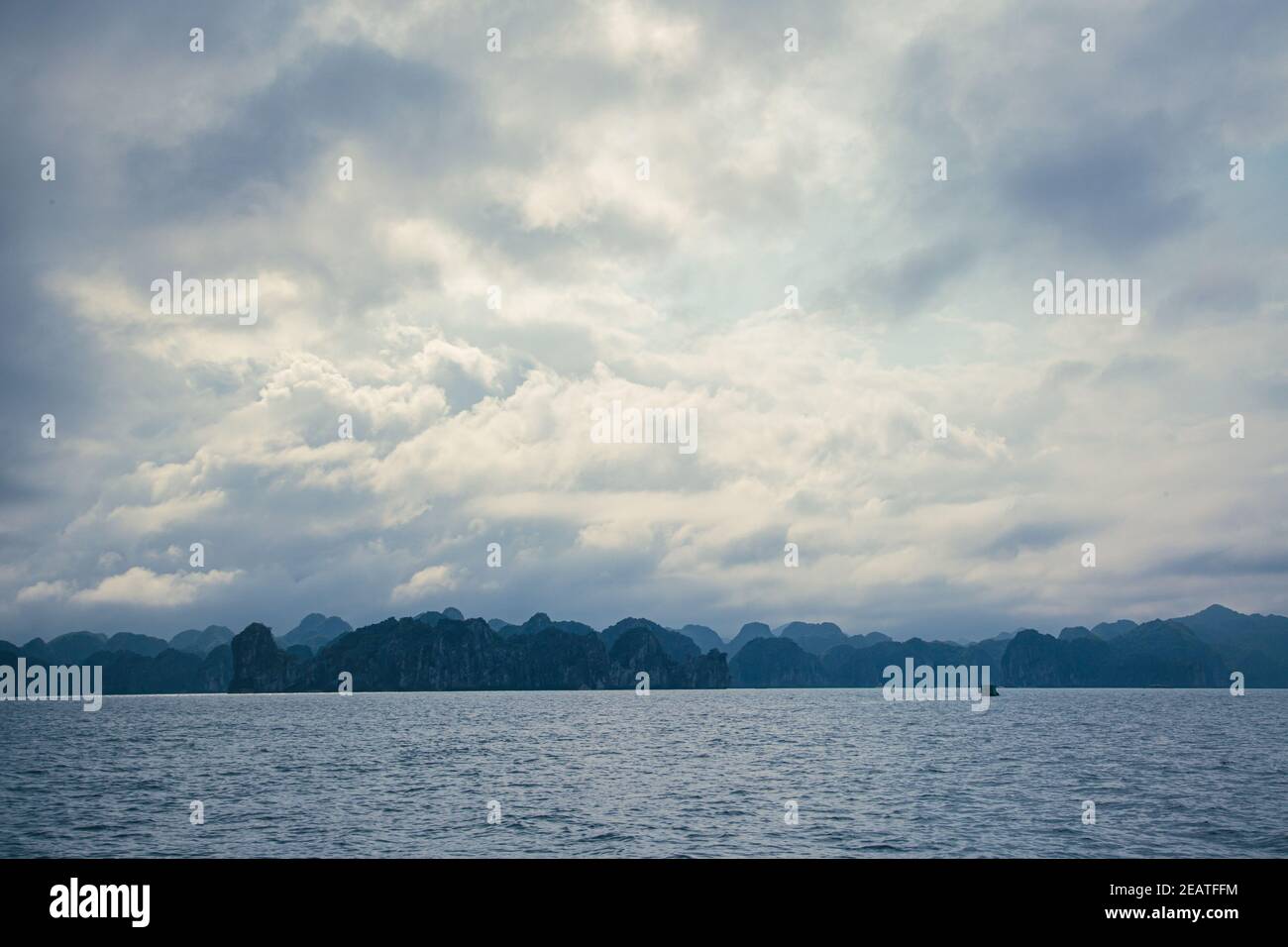 Vietnam paesaggio nuvoloso con strane montagne all'orizzonte sopra l'acqua Foto Stock