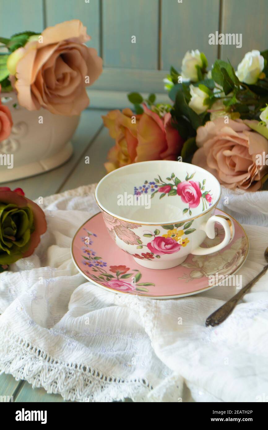 Tazza da tè vintage in porcellana su tavolo di legno con rose Foto Stock