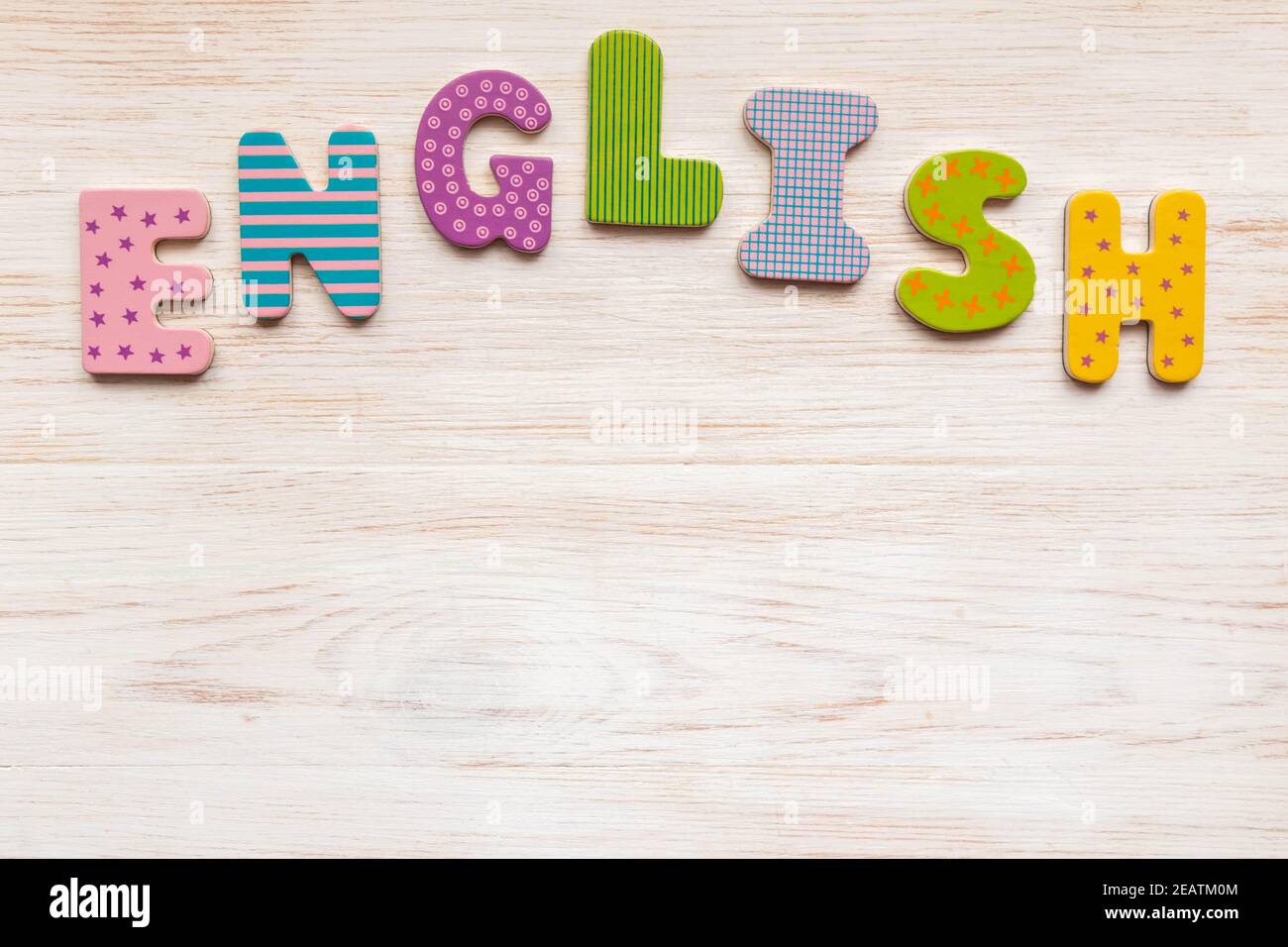 Parola inglese di colorate lettere in legno disposte su bianco dipinto legno vintage sfondo. Spazio di copia. Disposizione piatta, vista dall'alto Foto Stock