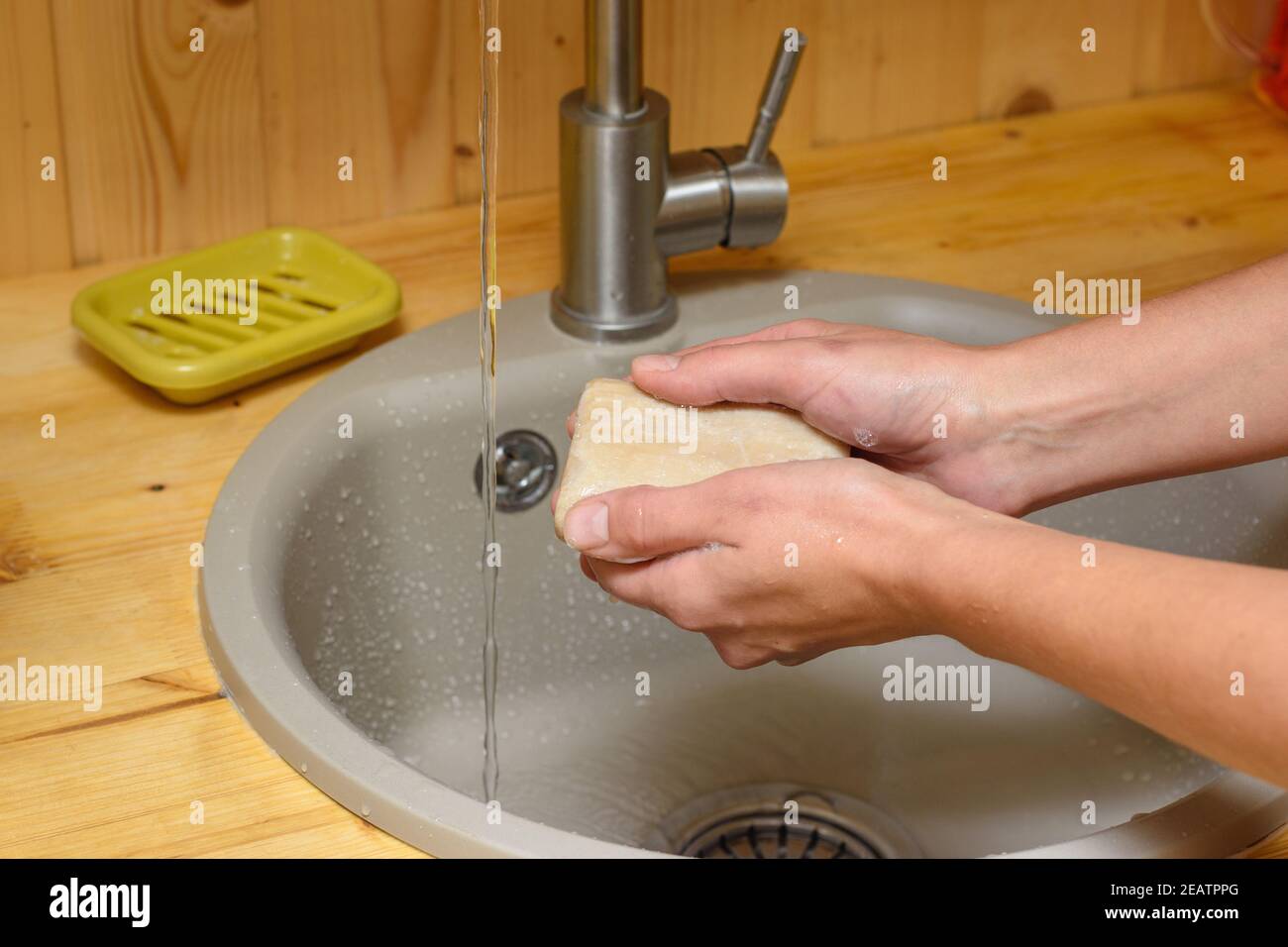 Le mani della ragazza che si inzuppano le mani con sapone in cucina lavello Foto Stock
