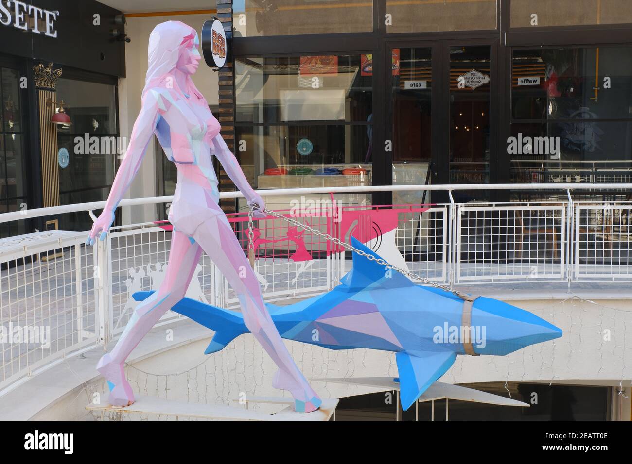 Scultura colorata al centro commerciale -giovane donna che cammina uno squalo- Foto Stock