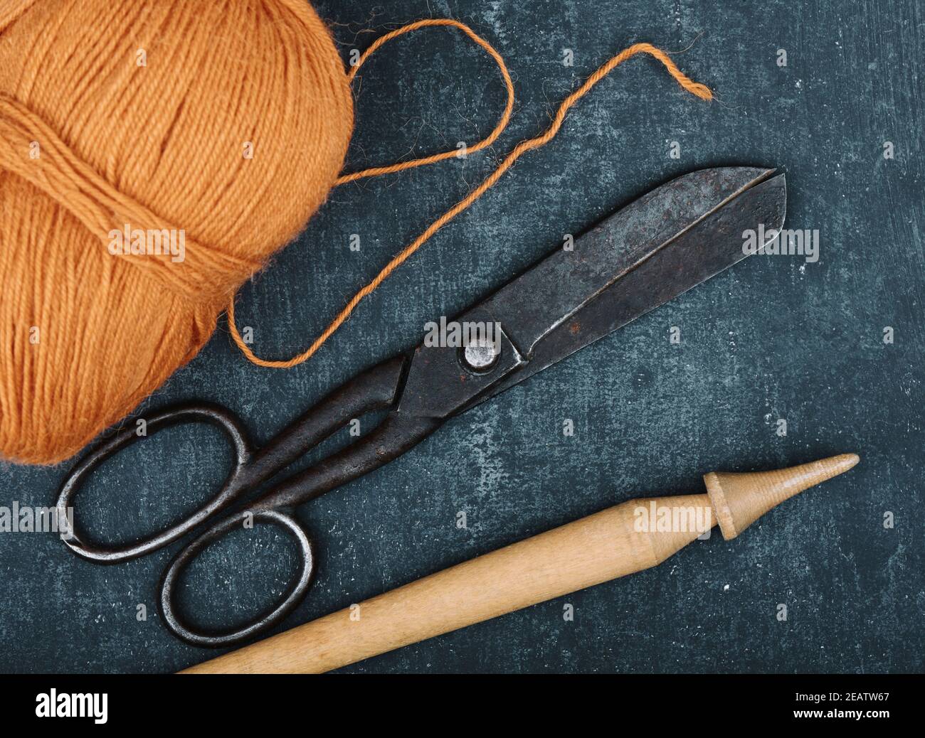 Antiche forbici da sarto arrugginite, groviglio di filo di lana di colore  arancio e fuso su sfondo grigio, primo piano Foto stock - Alamy