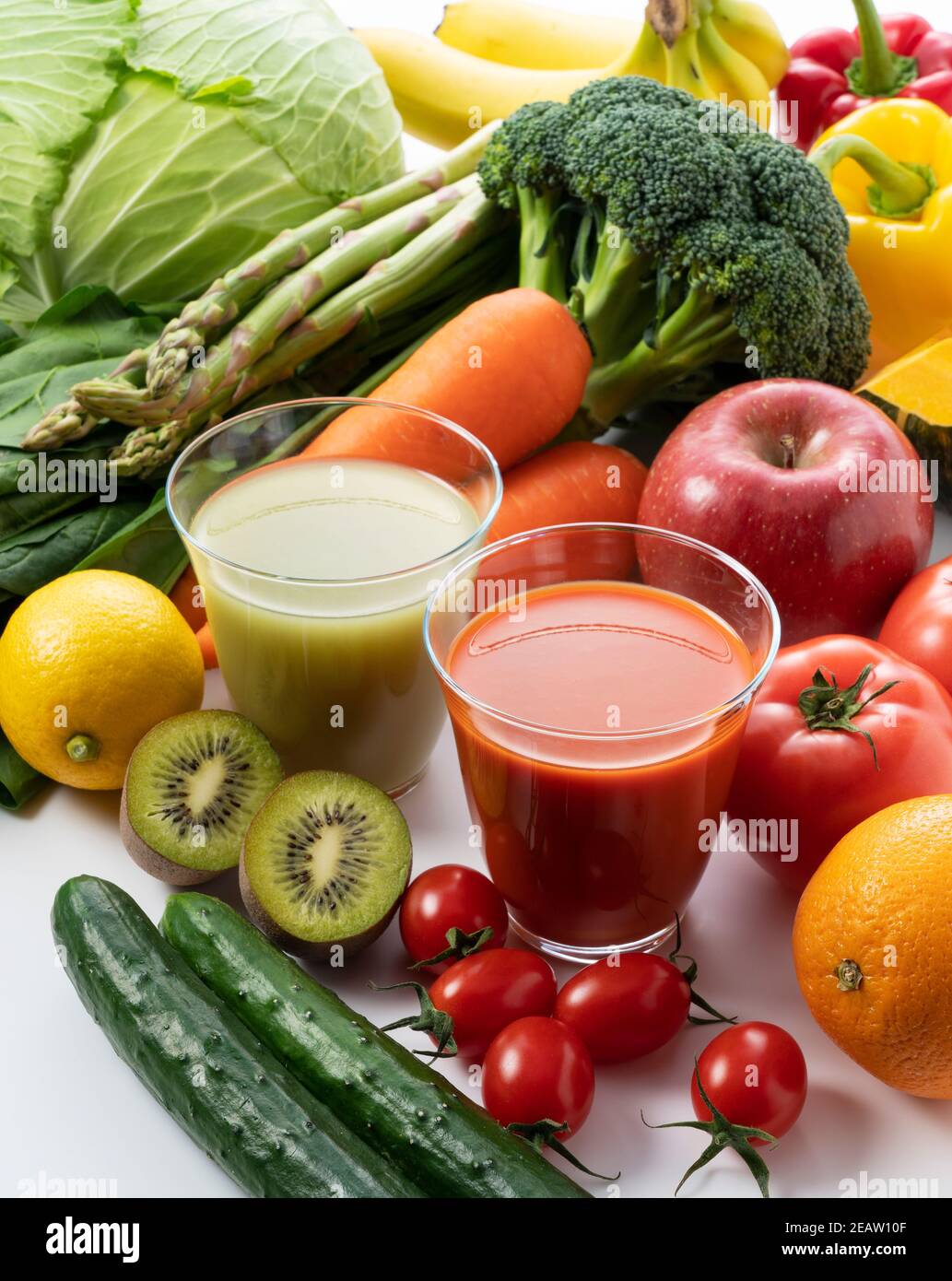 Un sacco di frutta e verdura su uno sfondo bianco con un bicchiere di frullato verde e succo di verdure Foto Stock