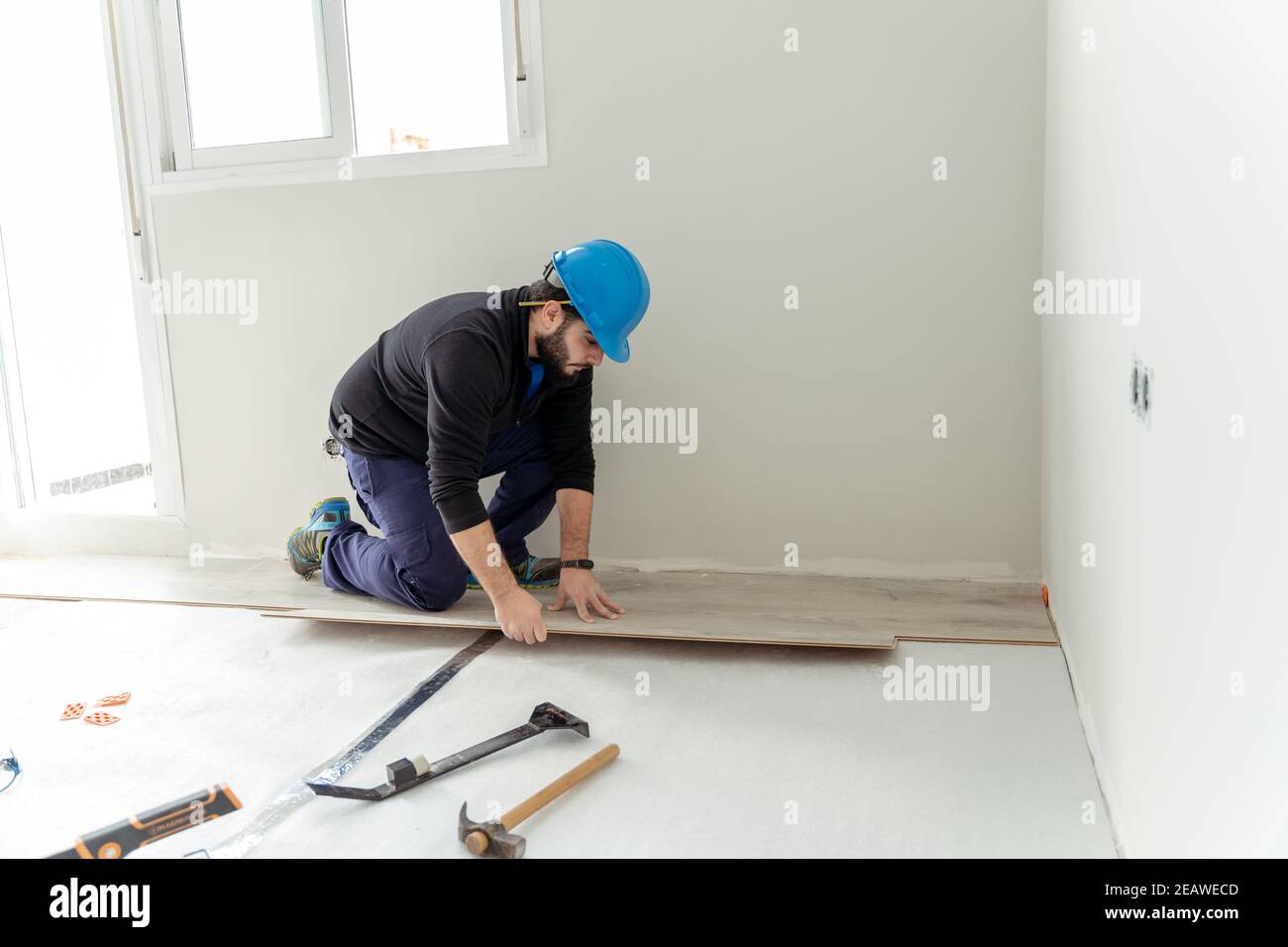Uomo lavoratore che assembla pavimenti laminati. Foto Stock