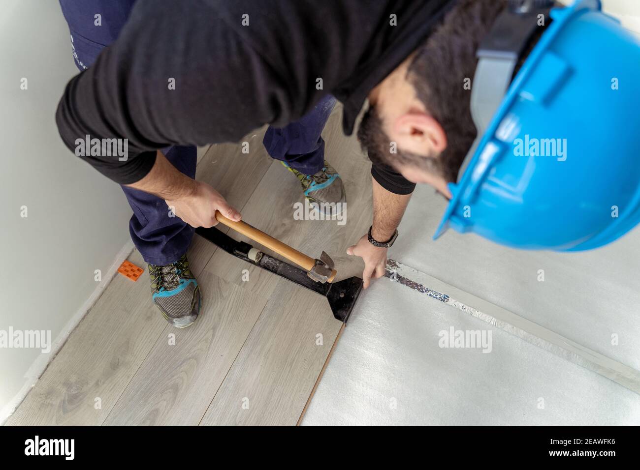 Uomo lavoratore che assembla pavimenti laminati. Foto Stock