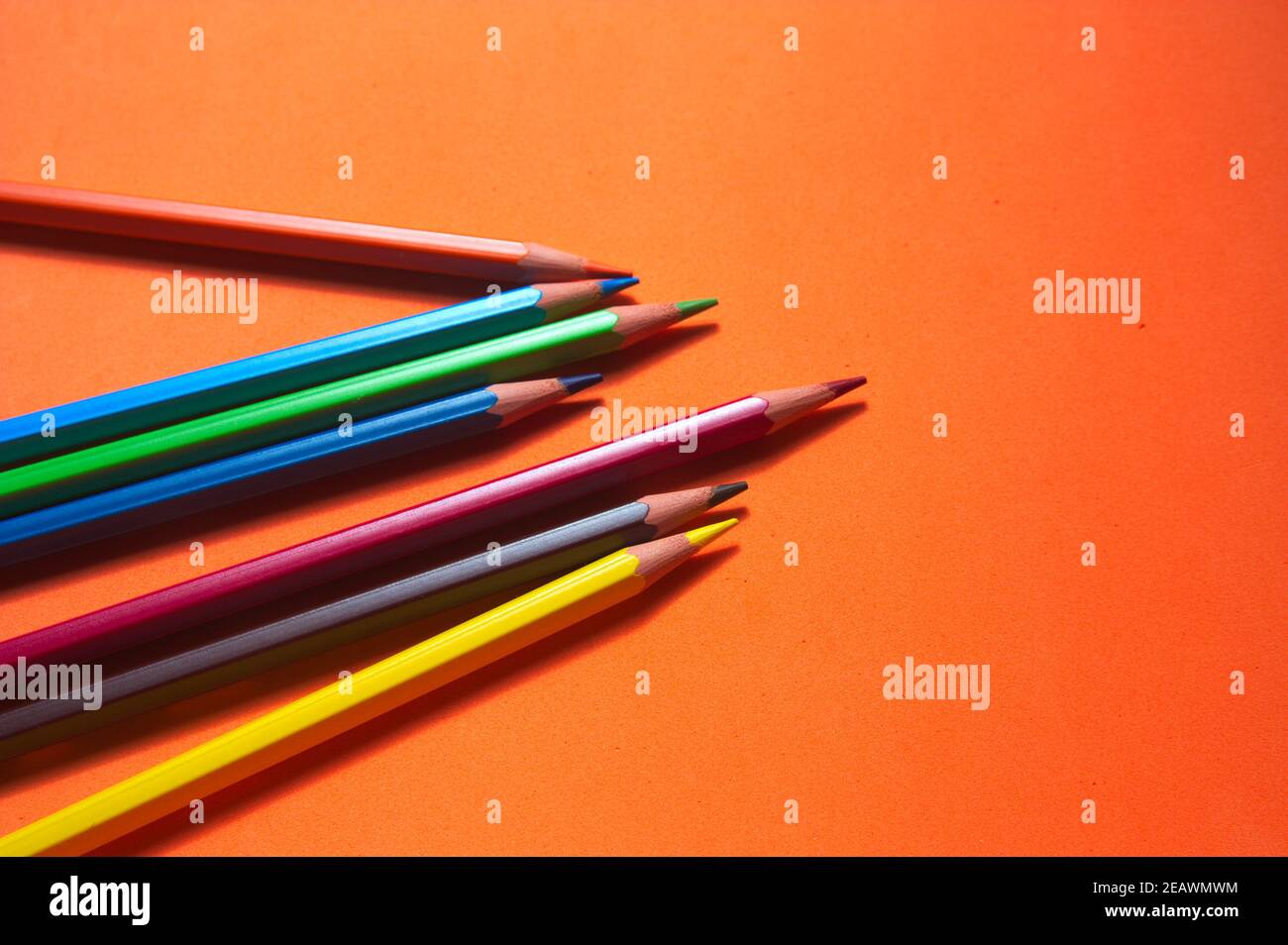 Un gruppo di pitture colorate su una superficie arancione e con spazio per la copia Foto Stock