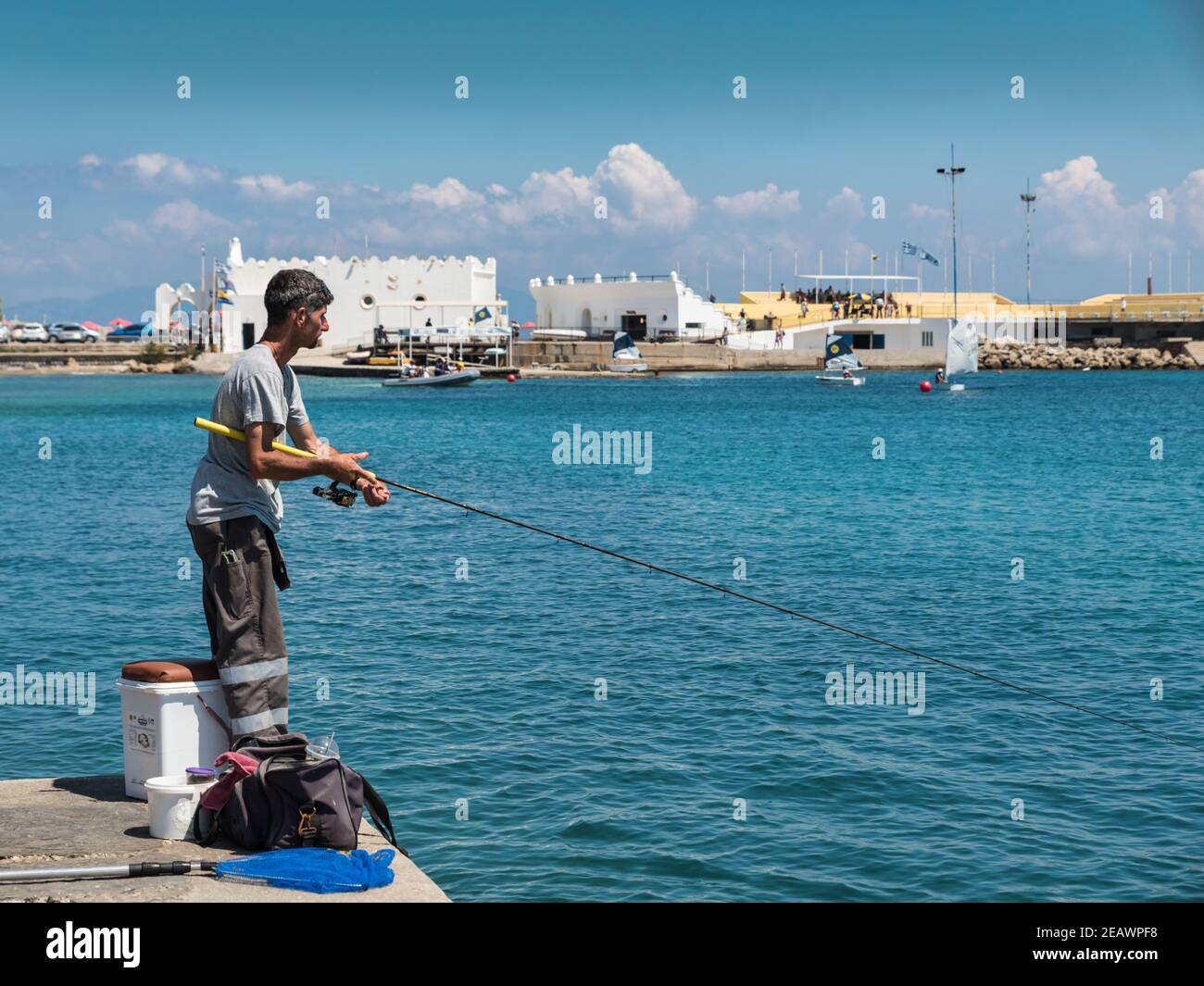 Rodi, Grecia - 25 luglio 2018: Uomo greco pesca al largo di un molo in Grecia Foto Stock