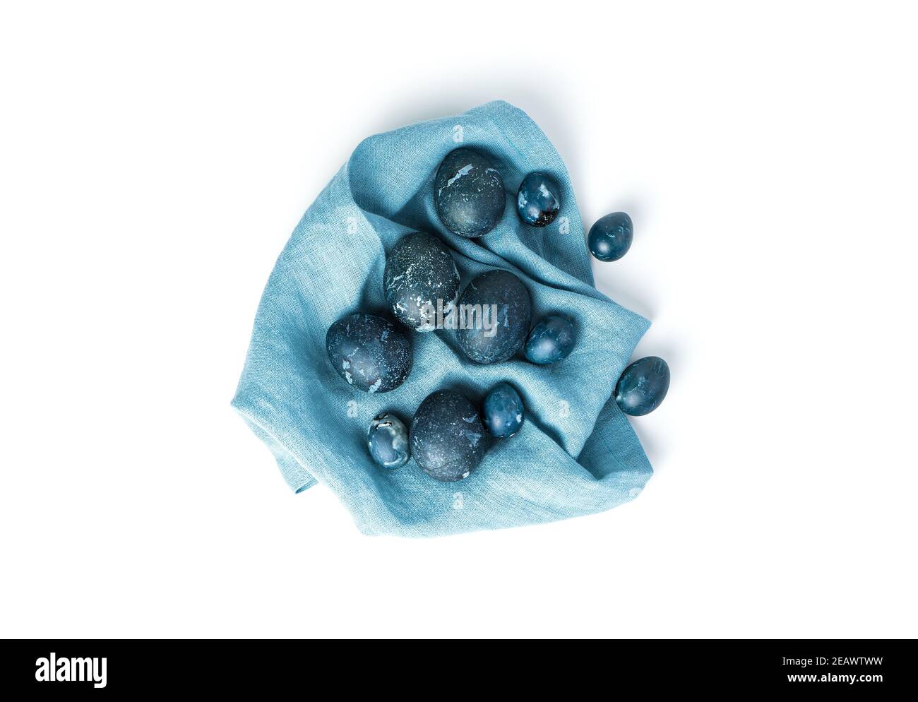 Le uova di quaglia e di pollo sono blu marmorizzato su un tovagliolo blu isolato su uno sfondo bianco. Orizzontale. Foto Stock