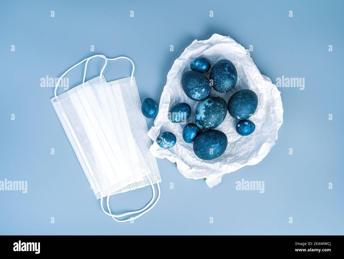 Quail e uova di pollo di colore blu in carta pergamena e maschere mediche su sfondo blu. Foto Stock