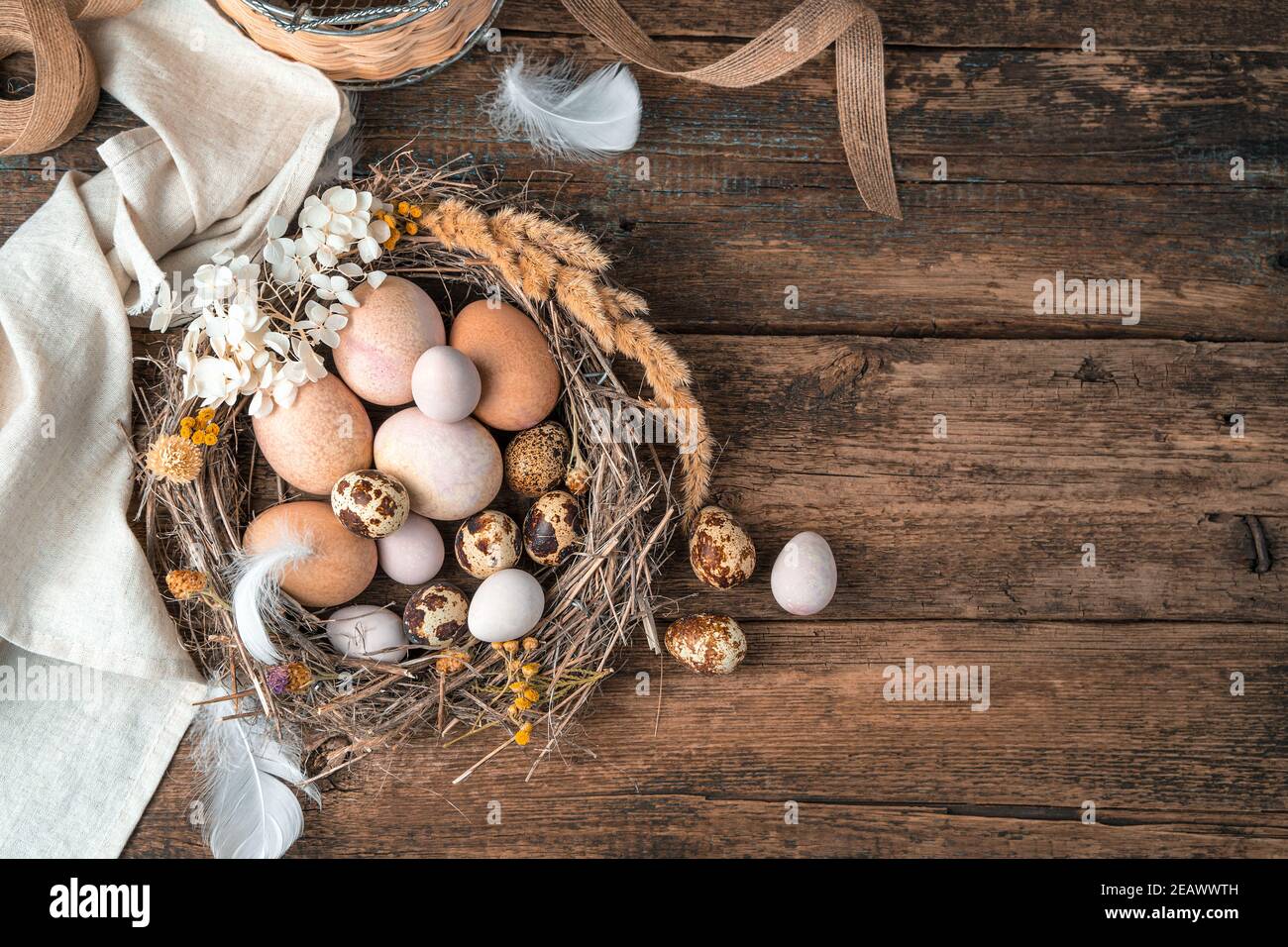 Buona Pasqua, sfondo festoso con uova in un nido su sfondo di legno. Foto Stock