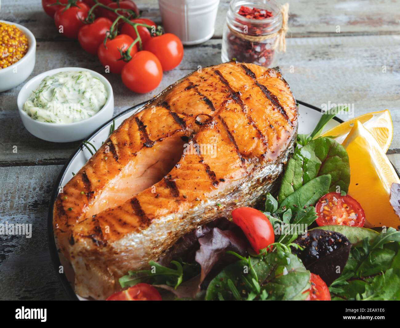 grigliate pesce bistecca di salmone con insalata fresca e pomodori, salsa bianca, vista dall'alto Foto Stock