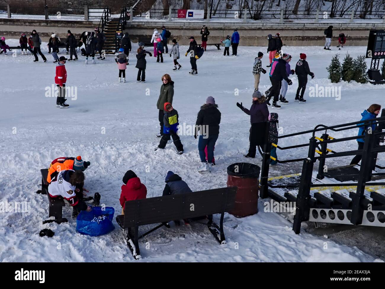 Pattinatori sulla pista più lunga del mondo che entrano o escono dai loro pattini. Rideau Canal, Ottawa, Ontario, Canada. Foto Stock