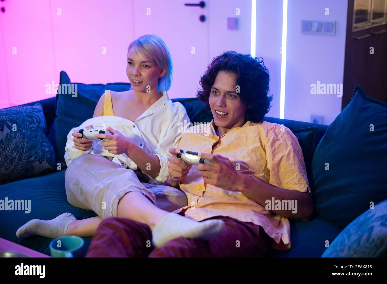 Ritratto di giovane coppia emozionale che gioca a videogame a casa. Foto Stock